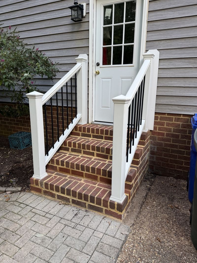 White stair railing with dark balusters on brick entry steps