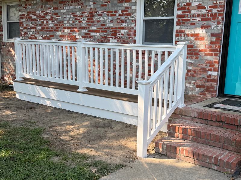 Low front deck with white railing and a white stair railing beside brick entry steps and a teal front door