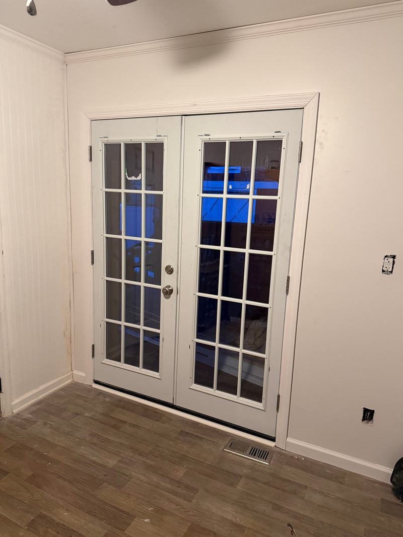Pair of white interior French doors with divided glass panels in a white room with wood-look floor