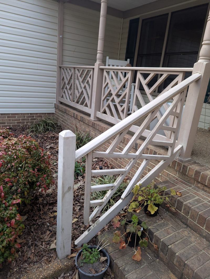 Broken white lattice-pattern porch stair railing over brick steps