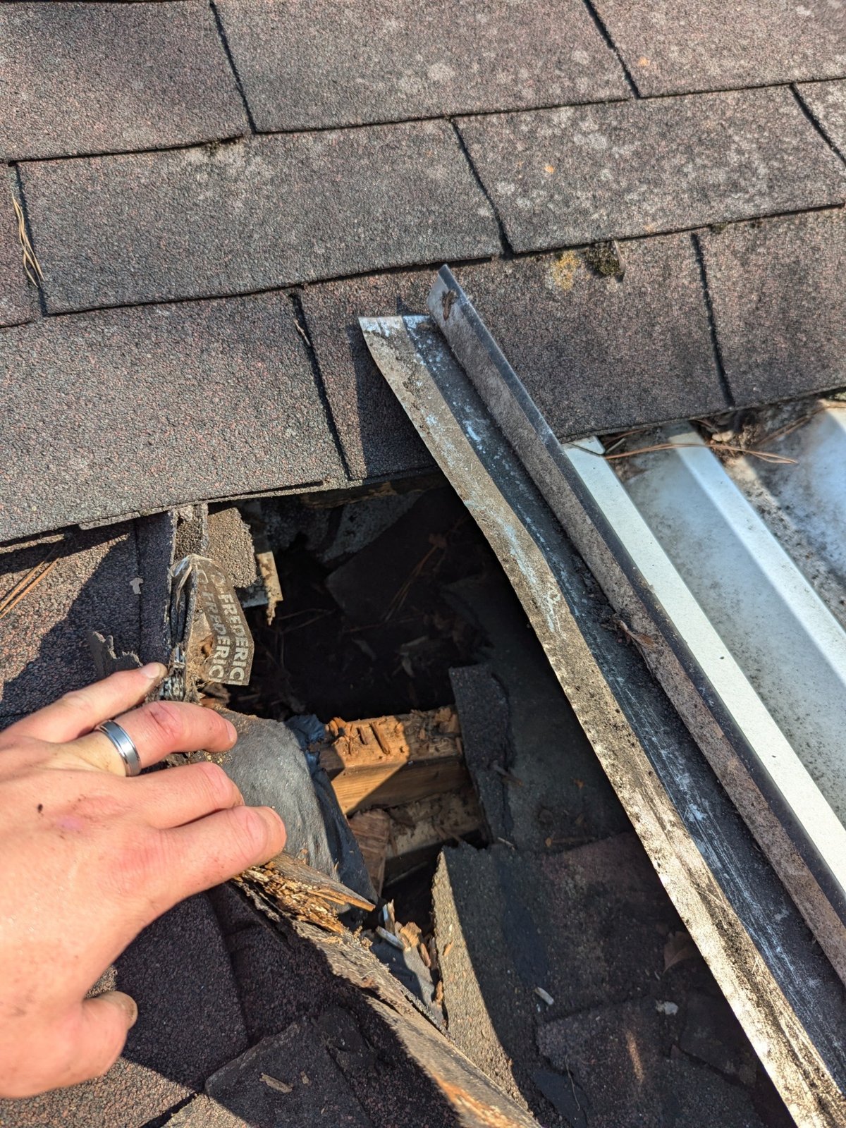 Roof opening exposing deteriorated wood under shingles and flashing